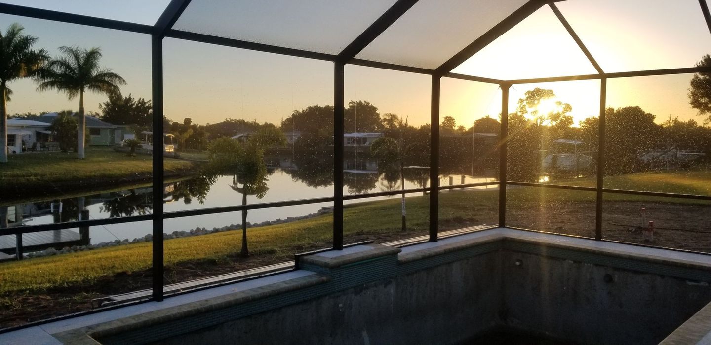 Aluminum pergola and screened outdoor living structure at sunset