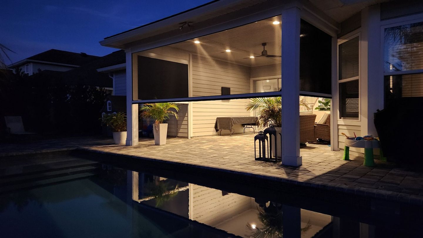 Retractable screen enclosure protecting a patio at night
